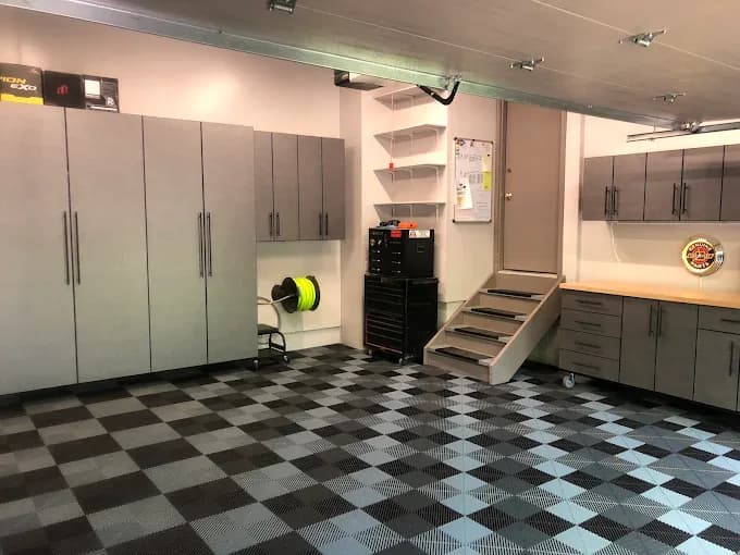 Finished garage with gray cabinets, a workbench, and a checkered tile floor