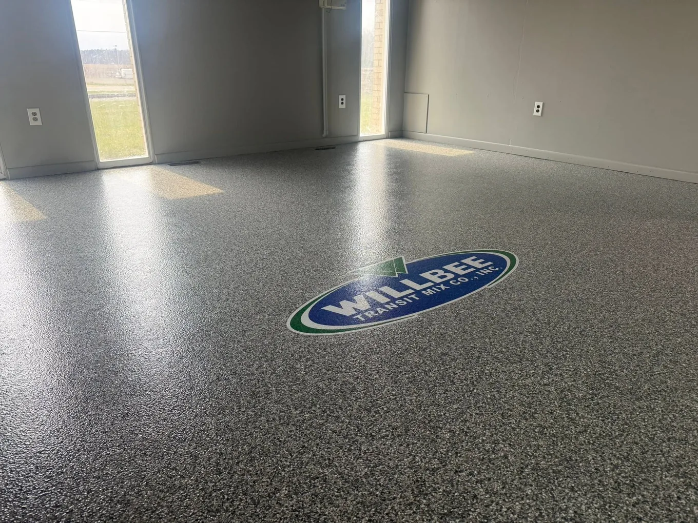 Showroom floor in dark flake with a company logo inlaid in the coating