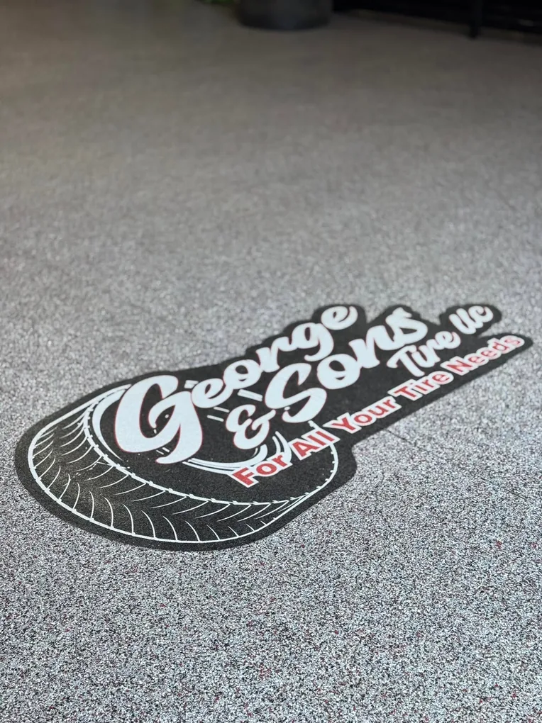Tire shop logo inlaid into a gray flake floor coating