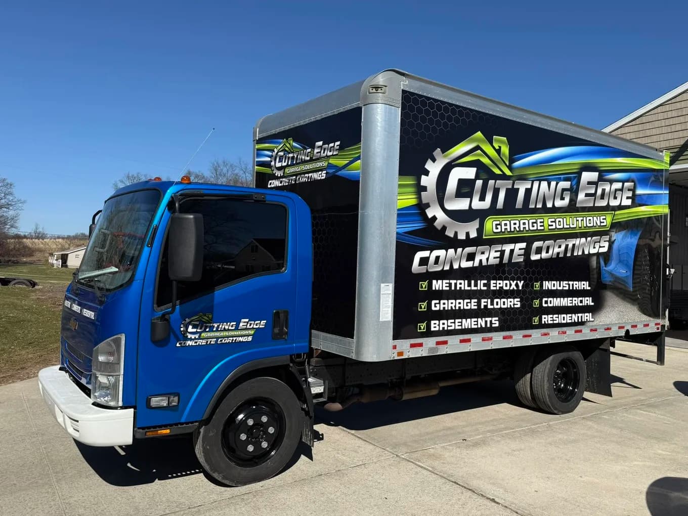 Cutting Edge Garage Solutions branded box truck parked on a freshly poured driveway