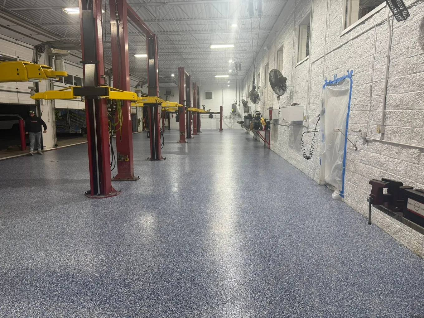 Industrial shop aisle with a blue-gray flake floor between work bays