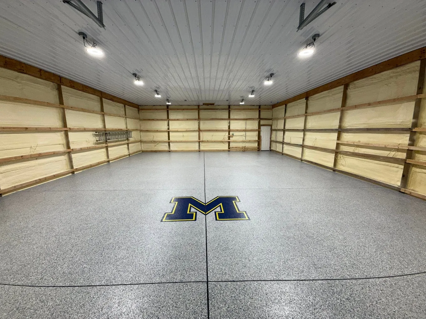 Pole barn floor in gray flake with a blue and gold block M inlay