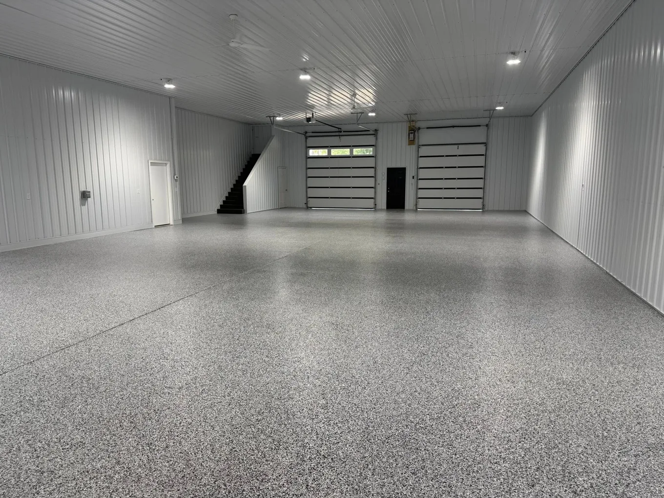 White-walled pole barn with a gray flake floor and overhead doors