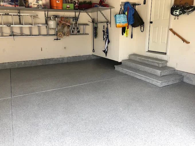 Coated garage floor with a slatwall tool wall beside the house entry