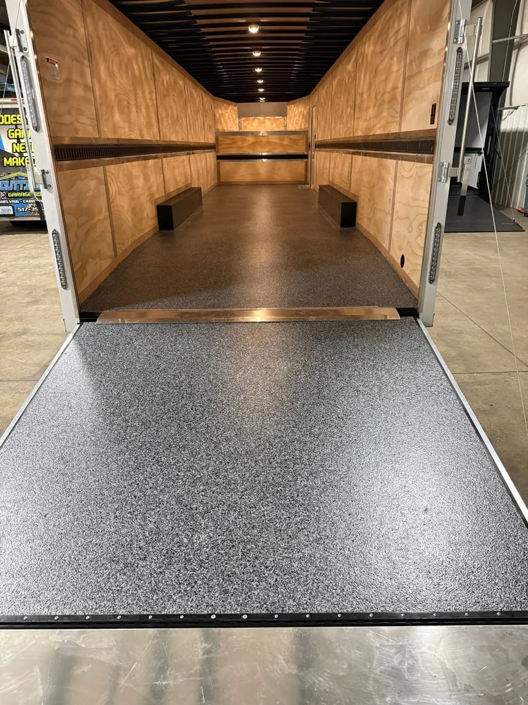 Wood-walled enclosed trailer with a freshly coated deck and open ramp