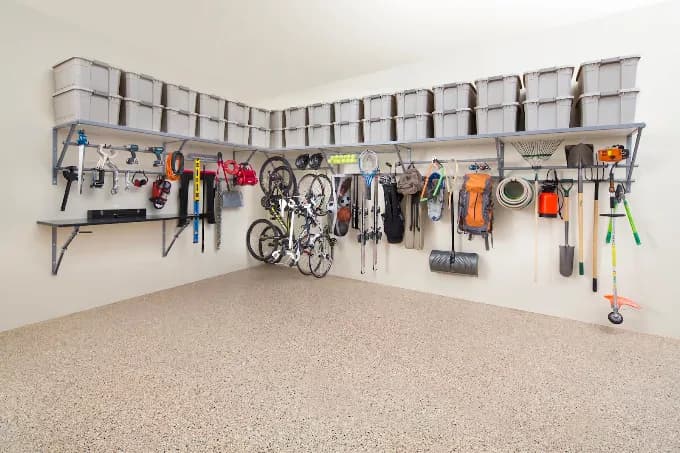 Wall shelving and hangers holding bins, bikes, and yard tools